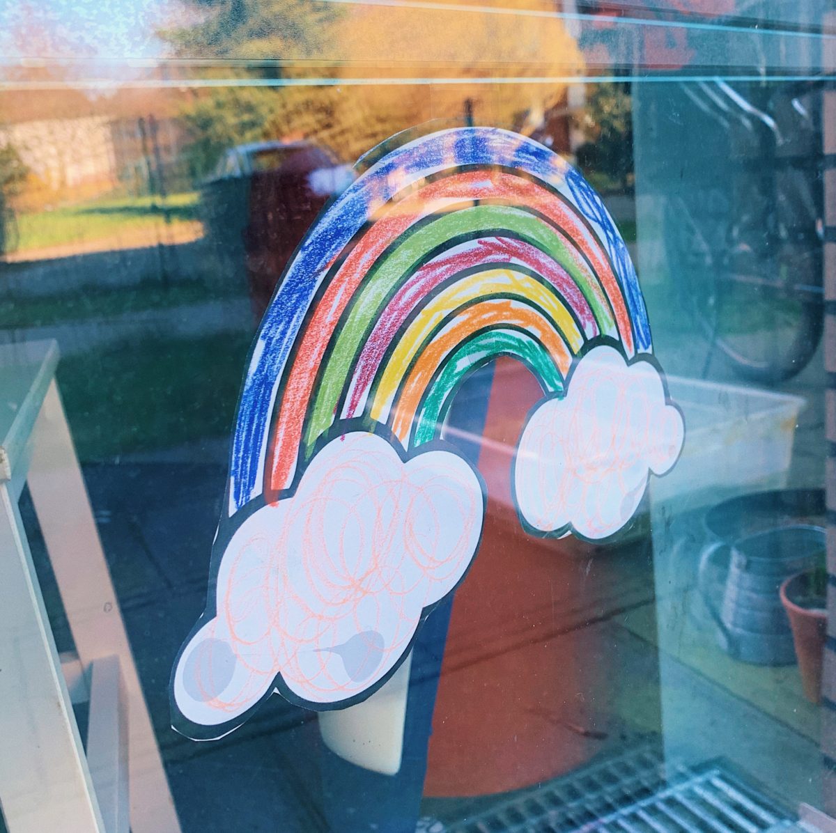 Ein bunter Regenbogen an einem Fenster, Symbol für Kinder die zu Hause bleiben.
